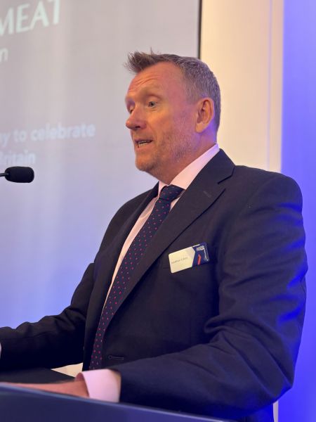 A man - Jonathan Eckley - standing at a microphone on a podium.